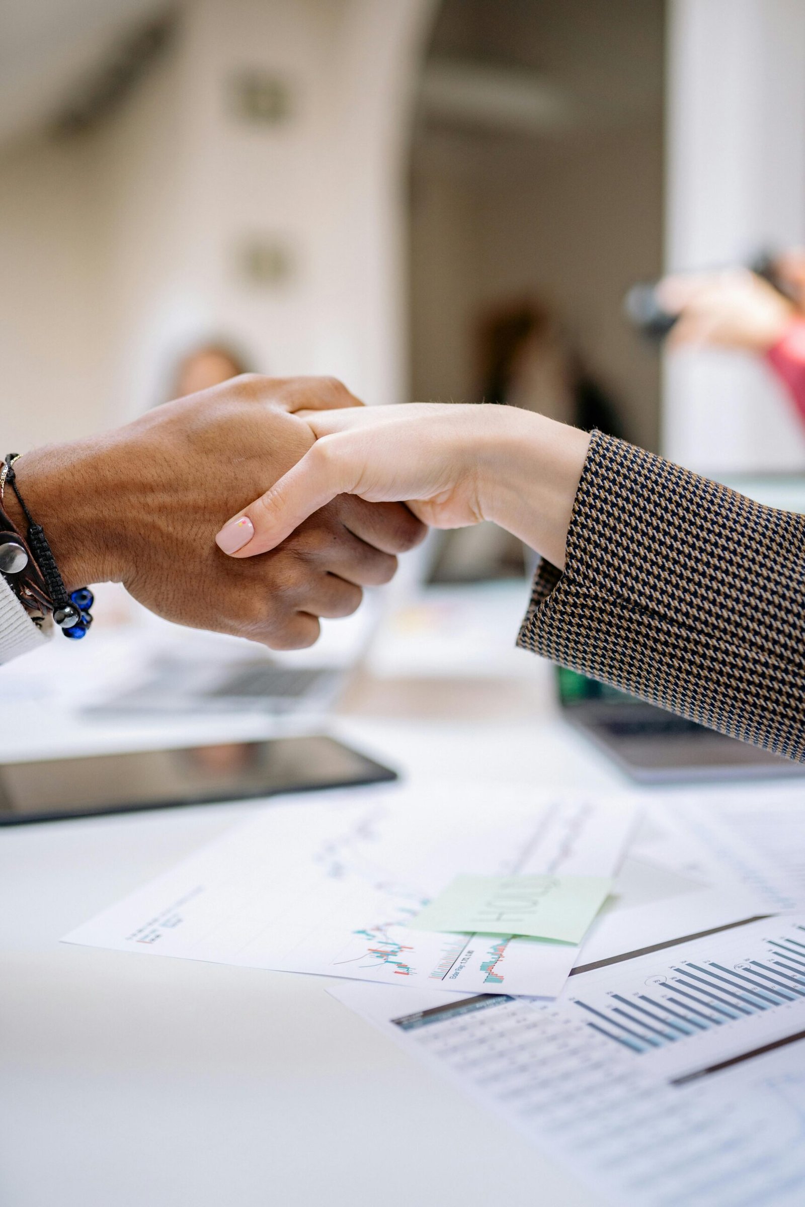 Close-up of a professional handshake over business documents, symbolizing partnership and agreement.